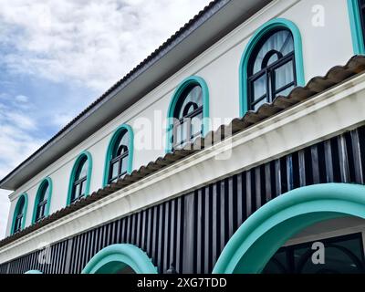 Weißes Gebäude mit Bogenfenstern und blauen Zierleisten steht hoch unter klarem Himmel Stockfoto