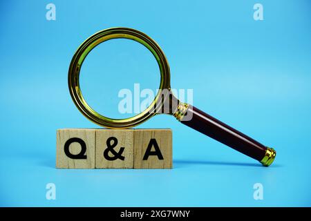 Fragen und Antworten (Frage und Antwort) mit Buchstaben aus Holzblöcken und Vergrößerungsglas auf blauem Hintergrund Stockfoto