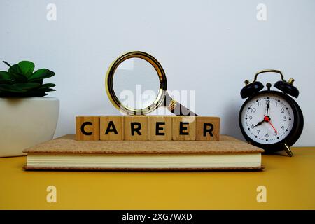 Lupe und Wecker mit Holzblöcken Alphabet Buchstaben KARRIERE Textnachricht auf gelbem Hintergrund Stockfoto