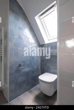 Kleine Toilette in Loft-Umbau mit cleverem Gebrauch der Traufe auf dem Dachboden. Architekt entworfen mit blauen Porzellan zellige Fliesen, weiße Wand hängende Toilette. Stockfoto