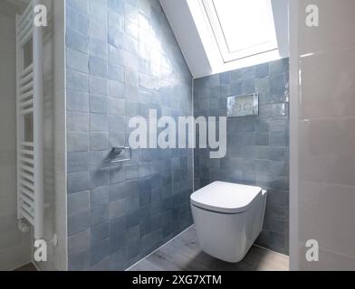 Kleine Toilette in Loft-Umbau mit cleverem Gebrauch der Traufe auf dem Dachboden. Architekt entworfen mit blauen Porzellan zellige Fliesen, weiße Wand hängende Toilette. Stockfoto