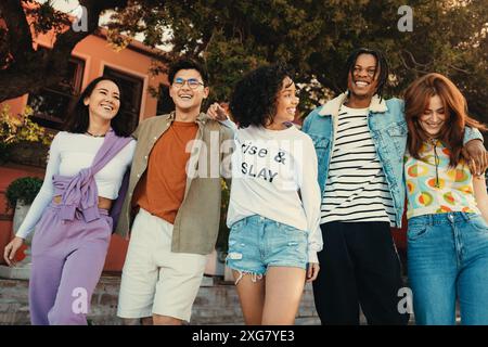 Eine Gruppe von Freunden, die Spaß haben, lachen und an einem sonnigen Sommertag gemeinsam in der Stadt spazieren gehen. Stockfoto