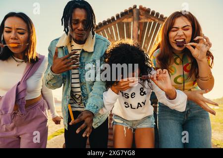 Gruppe von verschiedenen Freunden, die Spaß haben und an einem sonnigen Sommertag gemeinsam Eispops genießen. Stockfoto