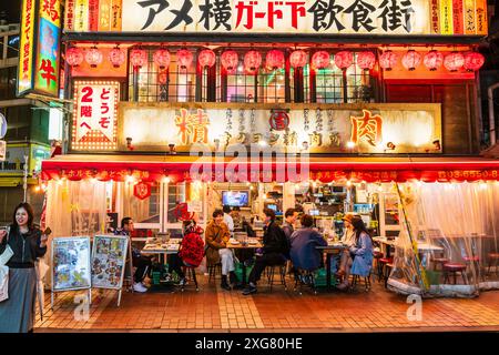 Großes, zweistöckiges japanisches Restaurant im beliebten Viertel Ueno Ameyoko in Tokio. Die Leute sitzen an Tischen vor dem Diner, essen und unterhalten sich. Stockfoto