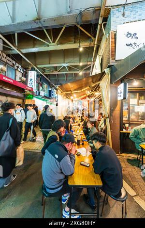 Sehen Sie am Tisch die Leute, die vor dem geschäftigen Gyukatsu Motomura Ueno Tonkatsu Ramen Restaurant im beliebten Ameyoko Ueno Viertel in Tokio essen. Stockfoto