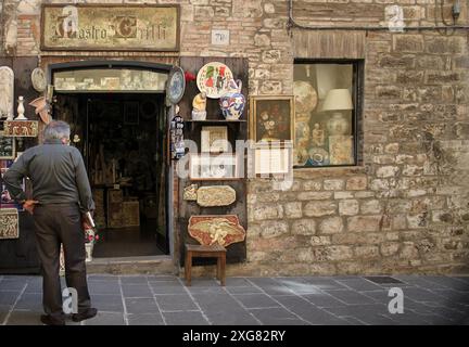 Gubbio, Italien - 3. Juli 2014: Ein Mann, der vor einem Souvenir- und Kunstgeschäft in Gubbio, Umbrien, Italien steht. Stockfoto