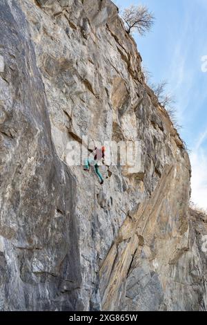 Kletterer klettert auf eine felsige Wand. Extremes Sportklettern. Stockfoto