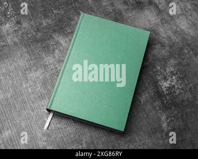 Grünes Buch mit festem Einband, das auf einem Holztisch nachgeahmt wird Stockfoto