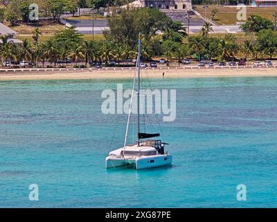 Einsamer Katamaran, der entlang flacher Gewässer auf den Bahamas vor Anker liegt, von einem Kreuzfahrtschiff aus gesehen Stockfoto