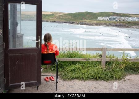 Ein RNLI-Rettungsschwimmer beobachtet Surfer oberhalb der Hayle Bay am 29. Juni in Polzeath, Cornwall, England. Stockfoto