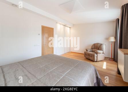 Luxuriöses Hauptschlafzimmer innen, modernes Haus, schöne Innenräume, großes Schlafzimmer. Sessel. Weitwinkel Stockfoto