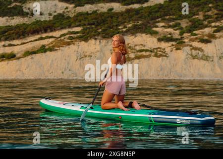 Juni 2021. Dalaman, Türkei. Sportliche Frau auf Stehpaddelbrett am Abend auf dem Meer. Frauen sitzen auf SUP-Board im Ozean. Stockfoto