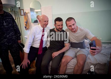 Odesa, Ukraine. Juli 2024. Der ukrainische Präsident Wolodymyr Zelenskyj, Zentrum, und der britische Verteidigungsminister John Healey, verließen ein Selfie mit einem verwundeten Krieger während eines Besuchs in einem Marinekrankenhaus am 7. Juli 2024 in Odesa, Ukraine. Healey versprach der Ukraine neue Unterstützung durch die neue Labour-Regierung im Vereinigten Königreich. Kredit: Ukrainischer Ratsvorsitz/Pressestelle Des Ukrainischen Präsidenten/Alamy Live News Stockfoto