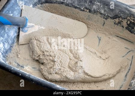 Nahaufnahme von frisch gemischtem Mörtel mit einer Kelle in einer Kunststoffrinne. Stockfoto