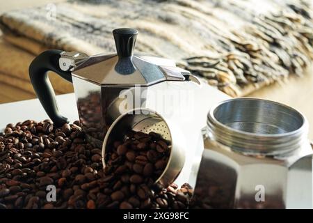 Italienische Mokkakanne (Caffettiera oder Macchinetta del Caffè), italienische Kaffeemaschine mit Kaffeebohnen im Hintergrund Stockfoto