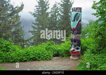Ein Totempfahl steht neben einem Weg durch einen nebeligen Wald auf einem Berg oberhalb von Juneau, Alaska Stockfoto