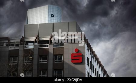 Sparkasse und Hauptquartier der Deutschen Bank, während dunkle Wolken vorbeiziehen. Finanzgeschäft in Deutschland. Unterzeichnen. Bankbranche in Frankfurt Stockfoto