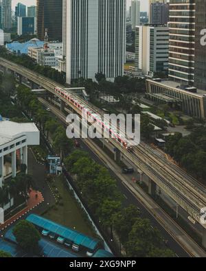 Jakarta, Indonesien - 12. Mai 2024. Eine Stadt in ständiger Bewegung. Ein roter Zug zieht durch die Stadtlandschaft, ein Symbol für den Fortschritt der Stadt und Stockfoto