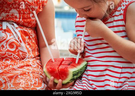 Kinder trinken Wassermelonensaft durch einen Strohhalm Stockfoto