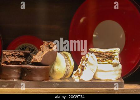 alfajores gefüllt mit weißer und dunkler Schokolade Dulce de leche auf einem Holzregal und dekorativen runden Kisten Stockfoto