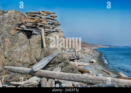 Ein Treibholzbau aus Baumstämmen steht auf einem Felsvorsprung, um über einen langen Strand in beide Richtungen zu blicken. Stockfoto