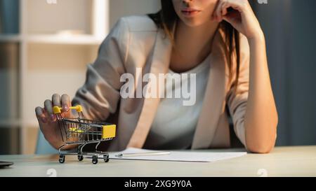 Fauler Mitarbeiter. Shopping-Tagtraum. Unglückliche gelangweilte Büroangestellte, die das Spielen des Spielzeugwagen am Arbeitsplatz aufschiebt und sich den Kauf wünscht. Stockfoto