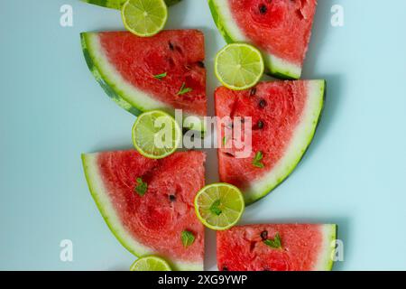 Lebendige Anordnung von Wassermelonenscheiben, Limettenscheiben und Minzblättern für ein frisches und sommerliches Gefühl Stockfoto