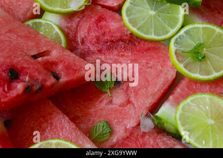Frische Wassermelonen- und Limettenscheiben, geschmückt mit Minzblättern, die eine erfrischende Sommeratmosphäre ausstrahlen Stockfoto
