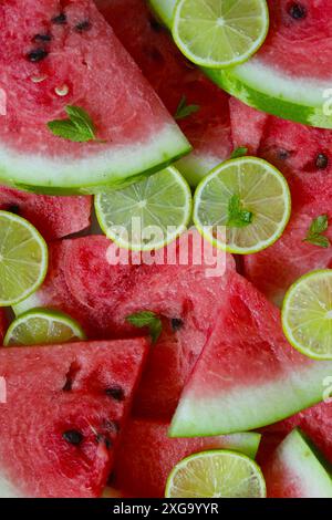 Eine Nahaufnahme von Wassermelonen- und Limettenscheiben, garniert mit Minzblättern, mit lebhaften Farben und einem erfrischenden Sommergefühl Stockfoto