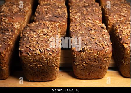 Auf einem Holzgestell-Hintergrund liegt eine Menge ganz leckeres hausgemachtes rechteckiges Roggenbrot mit Sonnenblumenkernen darauf Stockfoto