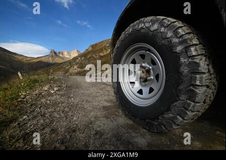 Nahaufnahme Ein großes Geländewagen-Rad steht auf einer rauen Straße in den Bergen vor dem Hintergrund von Felsen. Offroad-Touren und Offroad-Touren Stockfoto