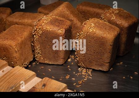 Auf einem Holzgestell-Hintergrund liegt eine Menge ganz leckeres hausgemachtes rechteckiges Roggenbrot mit Sonnenblumenkernen darauf Stockfoto