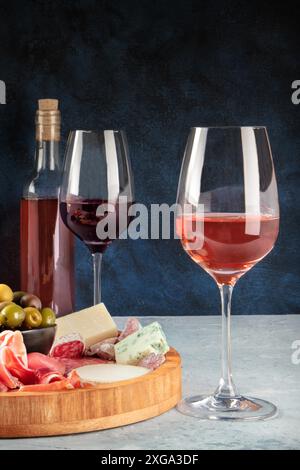 Wein, Käse, Wurstwaren und Oliven. Italienisches Antipasti-Buffet mit Gläsern Rose und Rotwein mit Blauschimmelkäse auf dunklem Hintergrund mit Platz Stockfoto