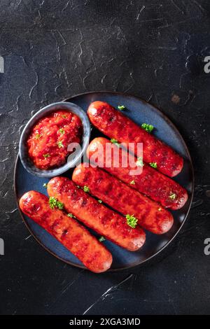 Gegrillte Würstchen mit Ketchup, von oben auf dunklem Hintergrund mit einem Platz für Text aufgenommen Stockfoto