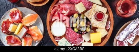 Wurst- und Käseplatte Panorama mit Rosen Wein- und Lachssandwiches, Top-shot auf schwarzem Hintergrund. Ein Panorama-Banner für einen Italiener Stockfoto