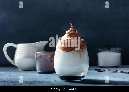 Dalgona kalter Kaffee mit Zutaten und Kopierraum, auf einem dunkelblauen Hintergrund. Süßes koreanisches Getränk Stockfoto