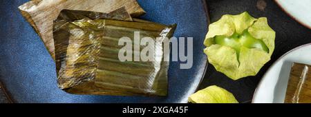 Tamalpanorama mit Tomatillo. Traditionelles Gericht der mexikanischen Küche, Flachbild-Lay-Shot mit Tomatillos. Verschiedene Füllungen in Grün gewickelt Stockfoto