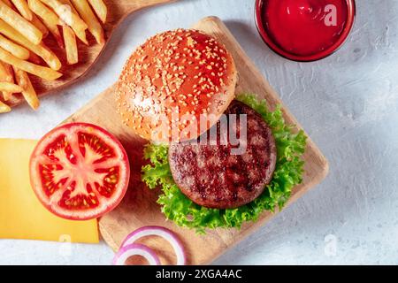 Hamburger Zutaten, von oben mit Pommes Frites und Ketchup auf einem rustikalen Holzbrett geschossen Stockfoto