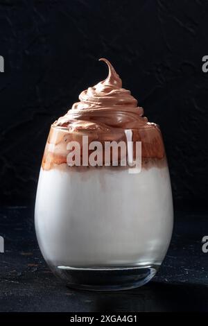 Dalgona kalter Kaffee in einem Glas auf schwarzem Hintergrund. Trendiger koreanischer Milchshake, Sommergetränk Stockfoto