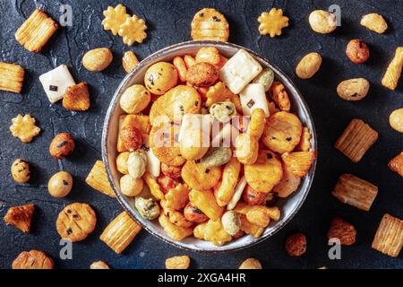 Japanische Reiscracker in einer Schüssel auf schwarzem Schieferhintergrund, oben flach hingelegt Stockfoto