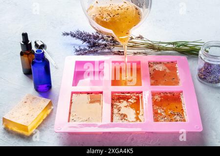 Handgemachte Bio-Seifenherstellung. DIY-Kosmetik, der Prozess der Herstellung. Flüssiges Glycerin mit ätherischen Ölen und Lavendelknospen wird in ein Silikon gegossen Stockfoto