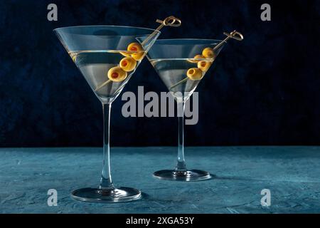 Martini, zwei Gläser mit würzigen Oliven, auf blauem Hintergrund. Kalte Getränke, Seitenblick Stockfoto