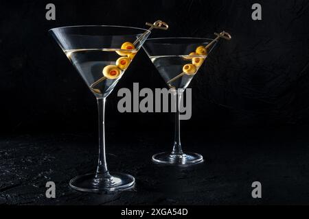 Martini, zwei Gläser mit würzigen Oliven, auf schwarzem Hintergrund. Kalte Getränke Stockfoto