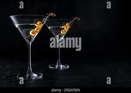 Martini, zwei Gläser mit würzigen Oliven, auf schwarzem Hintergrund. Alkoholische Getränke mit einem Platz für Text Stockfoto