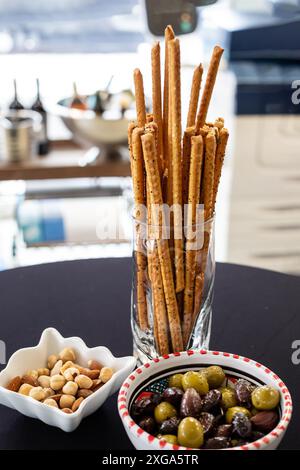 Brot klebt im Glas, Oliven und Erdnüsse am Bürotisch Stockfoto