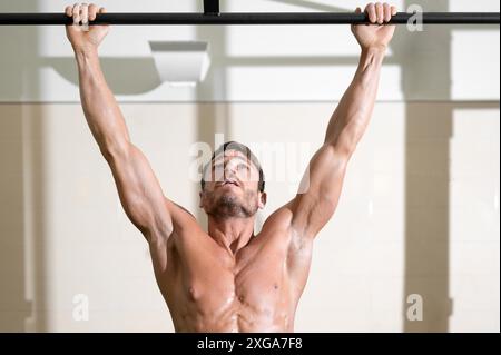 Ein Athlet, der im Fitnessstudio Pull-ups macht. Gutaussehender Mann, der funktionelles Training macht. Hochwertige Fotos Stockfoto