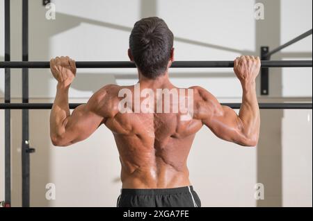 Ein Athlet, der im Fitnessstudio Pull-ups macht. Gutaussehender Mann, der funktionelles Training macht. Hochwertige Fotos Stockfoto