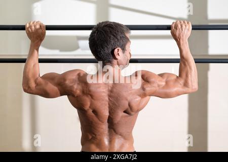 Ein Athlet, der im Fitnessstudio Pull-ups macht. Gutaussehender Mann, der funktionelles Training macht. Hochwertige Fotos Stockfoto