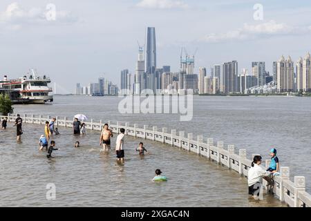 Wuhan, China. Juli 2024. Die Menschen spielen im überfluteten Hankou Riverbank Park am Yangtze. Die Wasserstände in Abschnitten des mittleren und unteren Flusses des Yangtze-Flusses - Chinas längster Fluss - unterhalb der Mündung des Dongting-Sees, haben laut dem Ministerium für Wasserressourcen die Warnmarke überschritten. Quelle: SOPA Images Limited/Alamy Live News Stockfoto