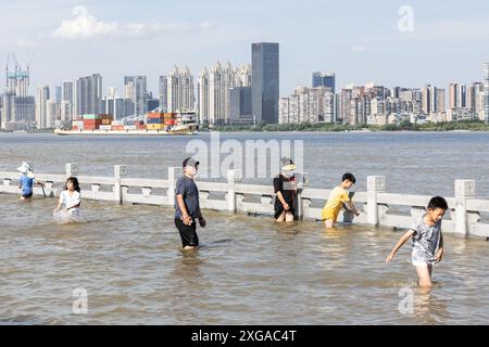 Wuhan, China. Juli 2024. Die Menschen spielen im überfluteten Hankou Riverbank Park am Yangtze. Die Wasserstände in Abschnitten des mittleren und unteren Flusses des Yangtze-Flusses - Chinas längster Fluss - unterhalb der Mündung des Dongting-Sees, haben laut dem Ministerium für Wasserressourcen die Warnmarke überschritten. Quelle: SOPA Images Limited/Alamy Live News Stockfoto